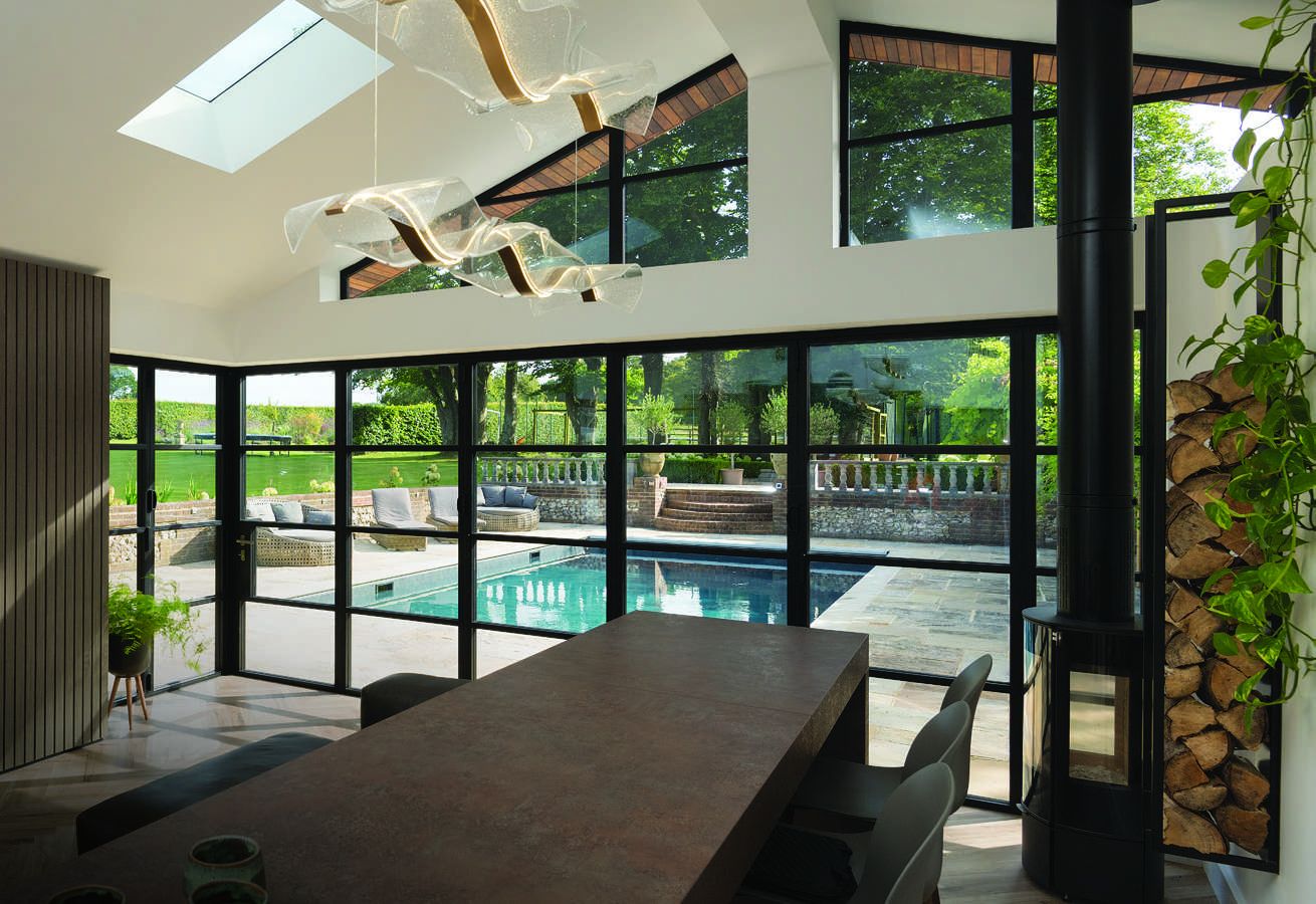 Corner bifold doors in jet black wrapping a poolside dining room